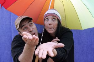 Foto einer Spielsequenz der Akteure unter einem bunten Regenschirm